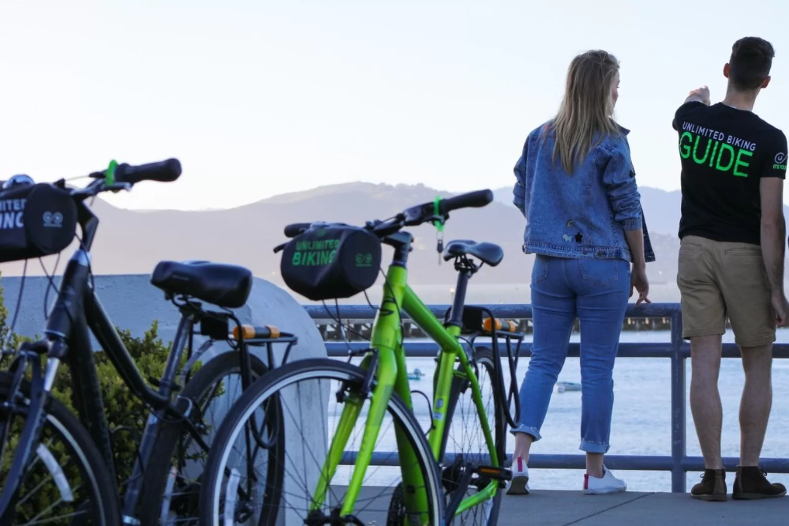 Cyclists and guide on display at Unlimited Biking rental overlooking the water and hills in San Francisco