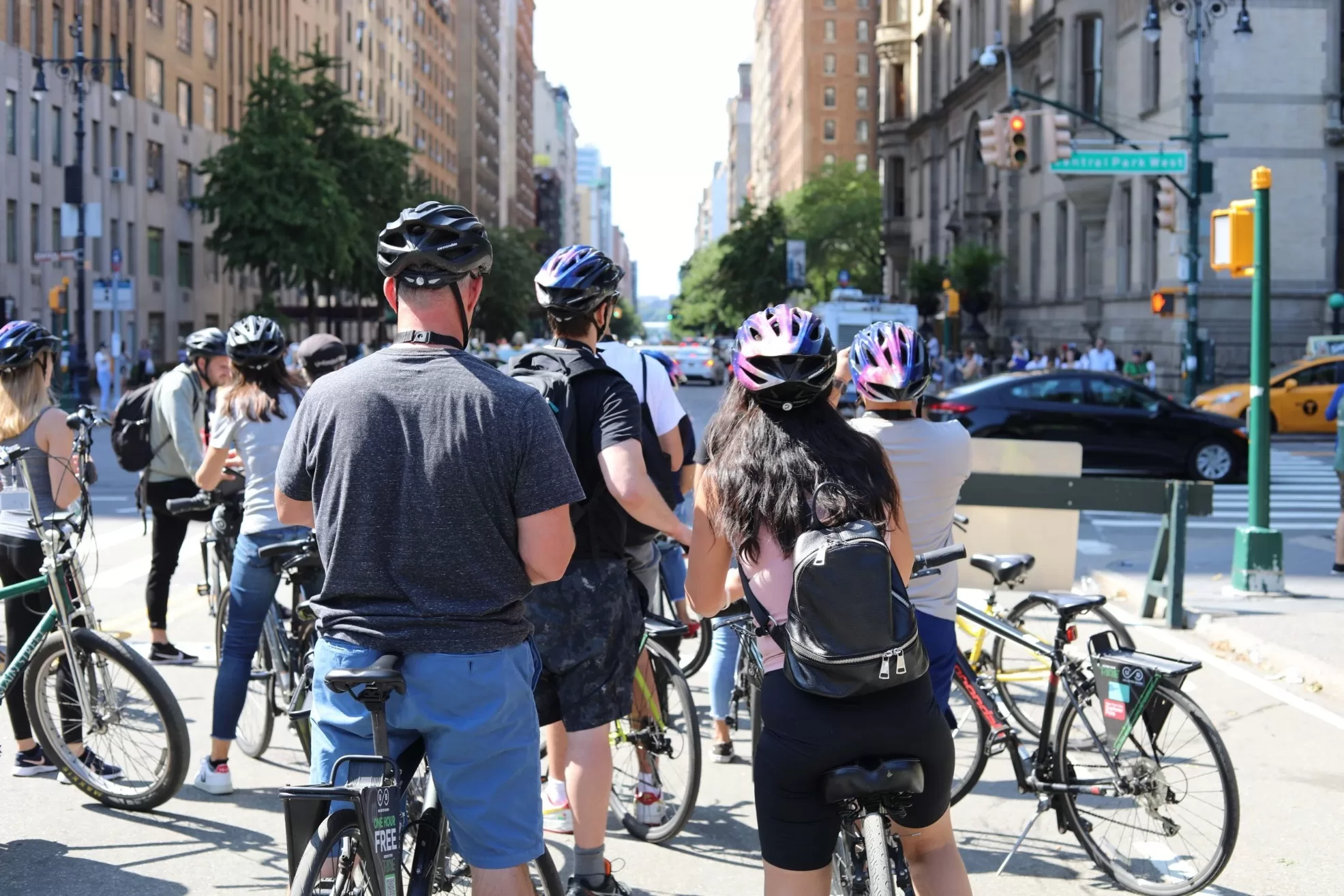 Groep fietsers met helmen wacht bij kruispunt in New York City, zonnige dag in druk stadsverkeer