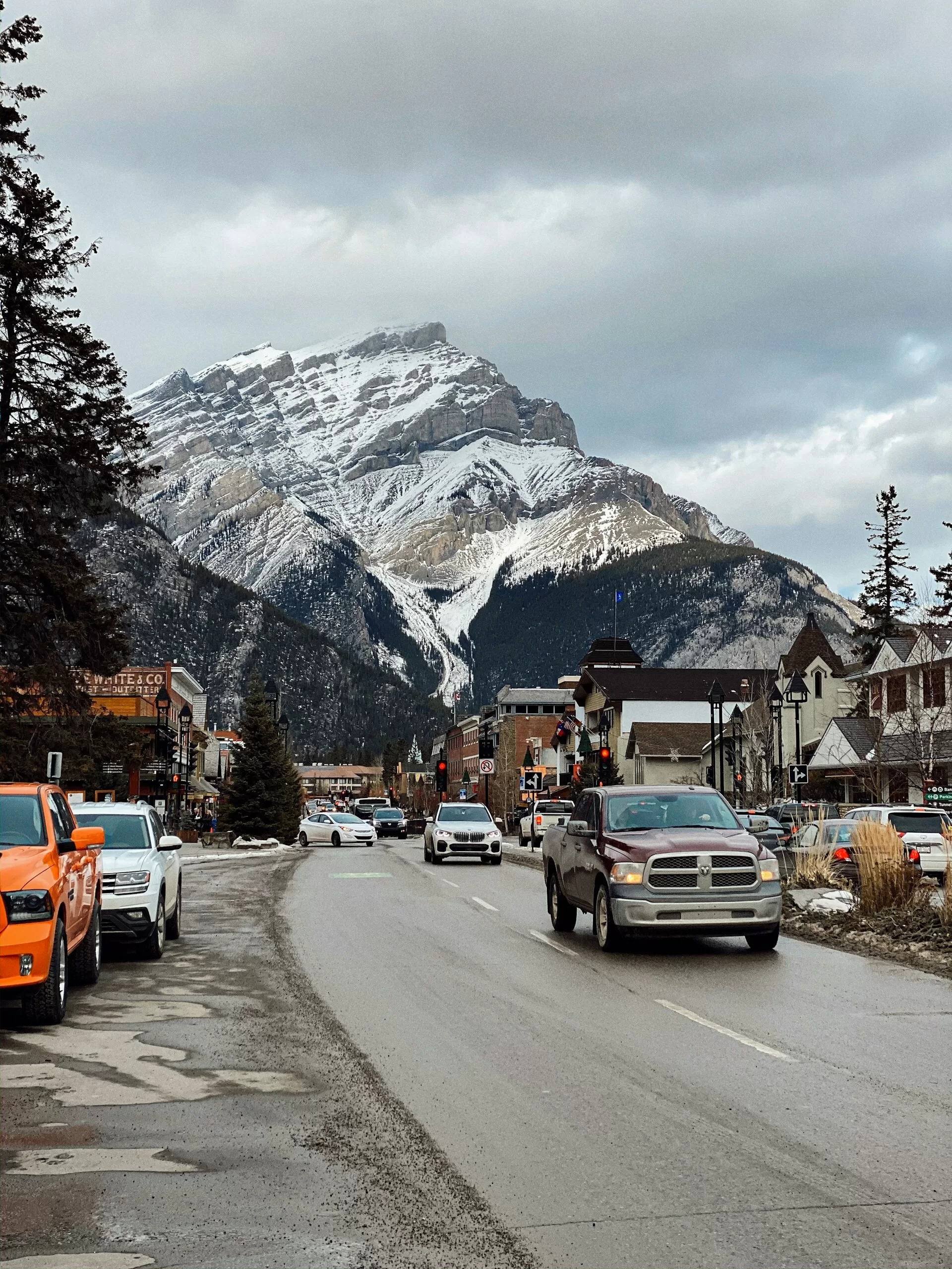 Een drukke straat in Banff met besneeuwde bergen op de achtergrond