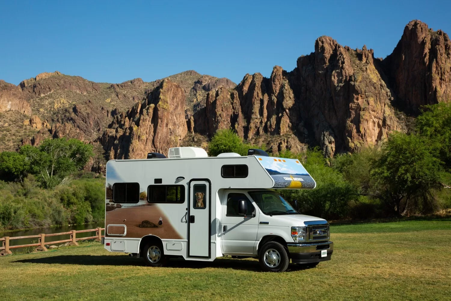 Een Cruise America camper in een weiland met rotsformaties op de achtergrond