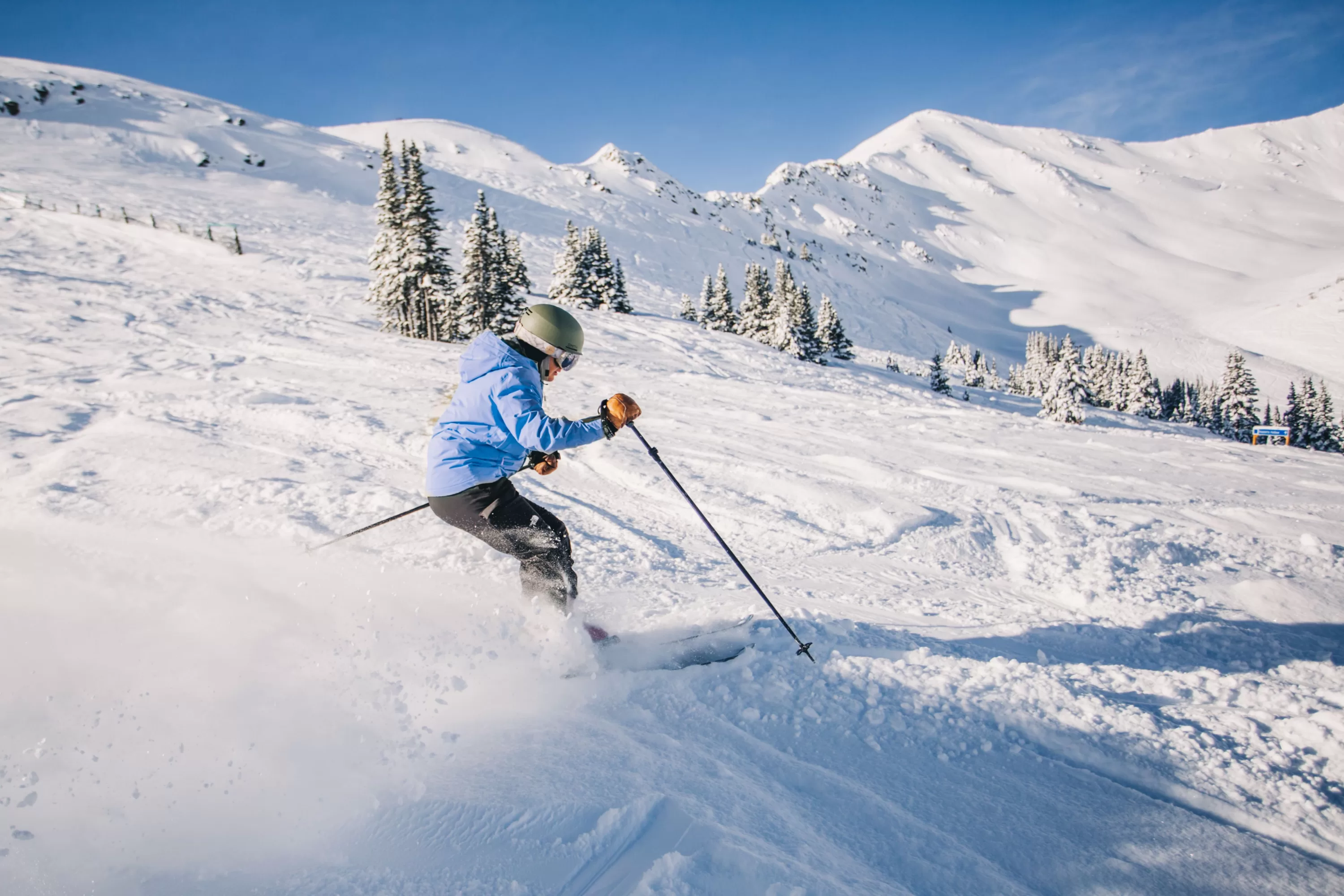 Een jongen die aan het skiën is in Jasper, Alberta, Canada, terwijl hij door de sneeuw glijdt met de bergen op de achtergrond