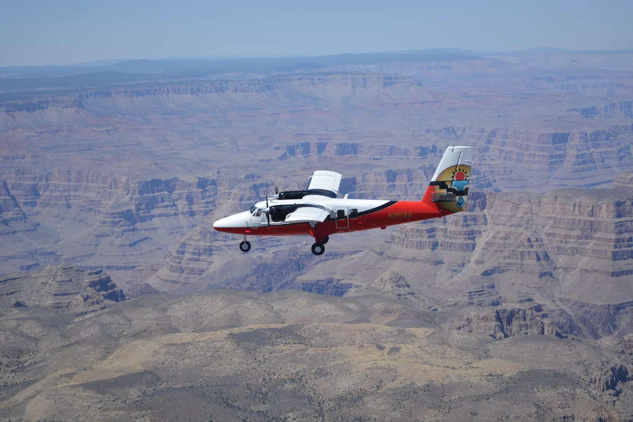 Rot-weißes Flugzeug fliegt über den Grand Canyon, Luftaufnahme von Felsformationen und tiefen Schluchten
