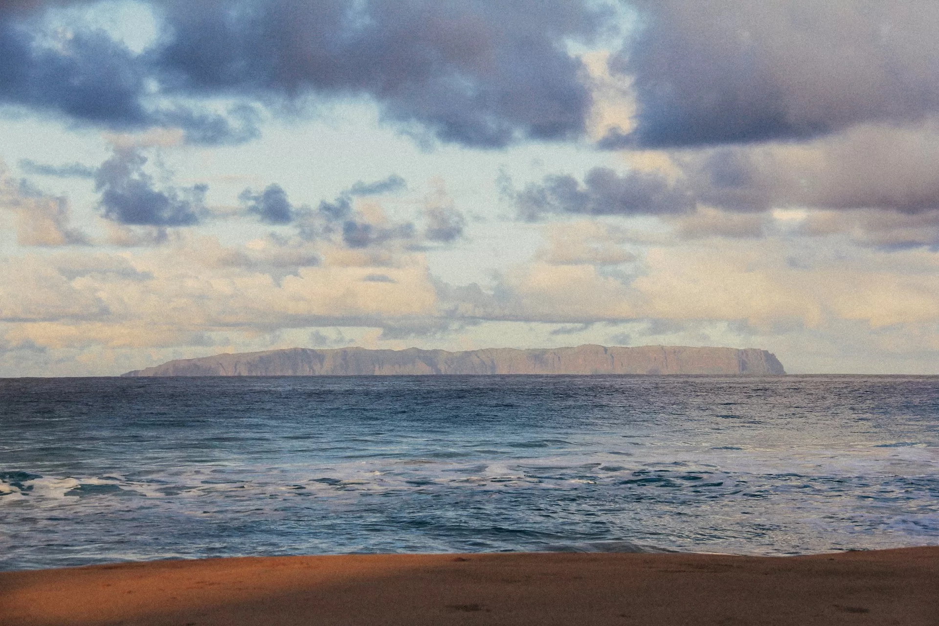Uitzicht op het Hawaïaanse eiland Niʻihau met zee en kustlijn zichtbaar op een bewolkte dag