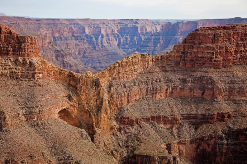 Grand Canyon mit freier Sicht auf die verschiedenfarbigen Gesteinsschichten und tiefen Schluchten unter blauem Himmel