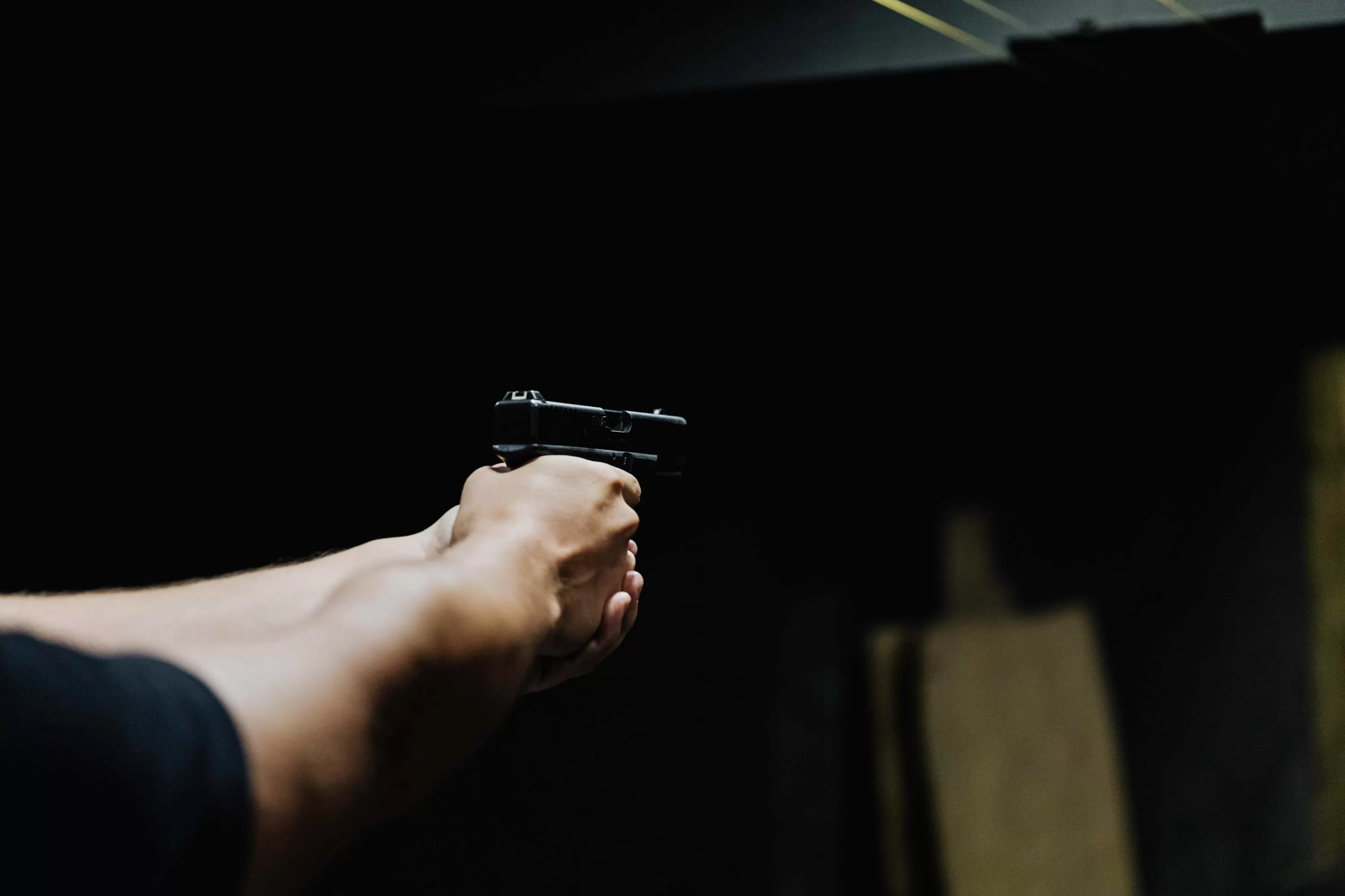 Nahaufnahme von Händen, die ein Gewehr während des Schießens auf einem Schießstand halten