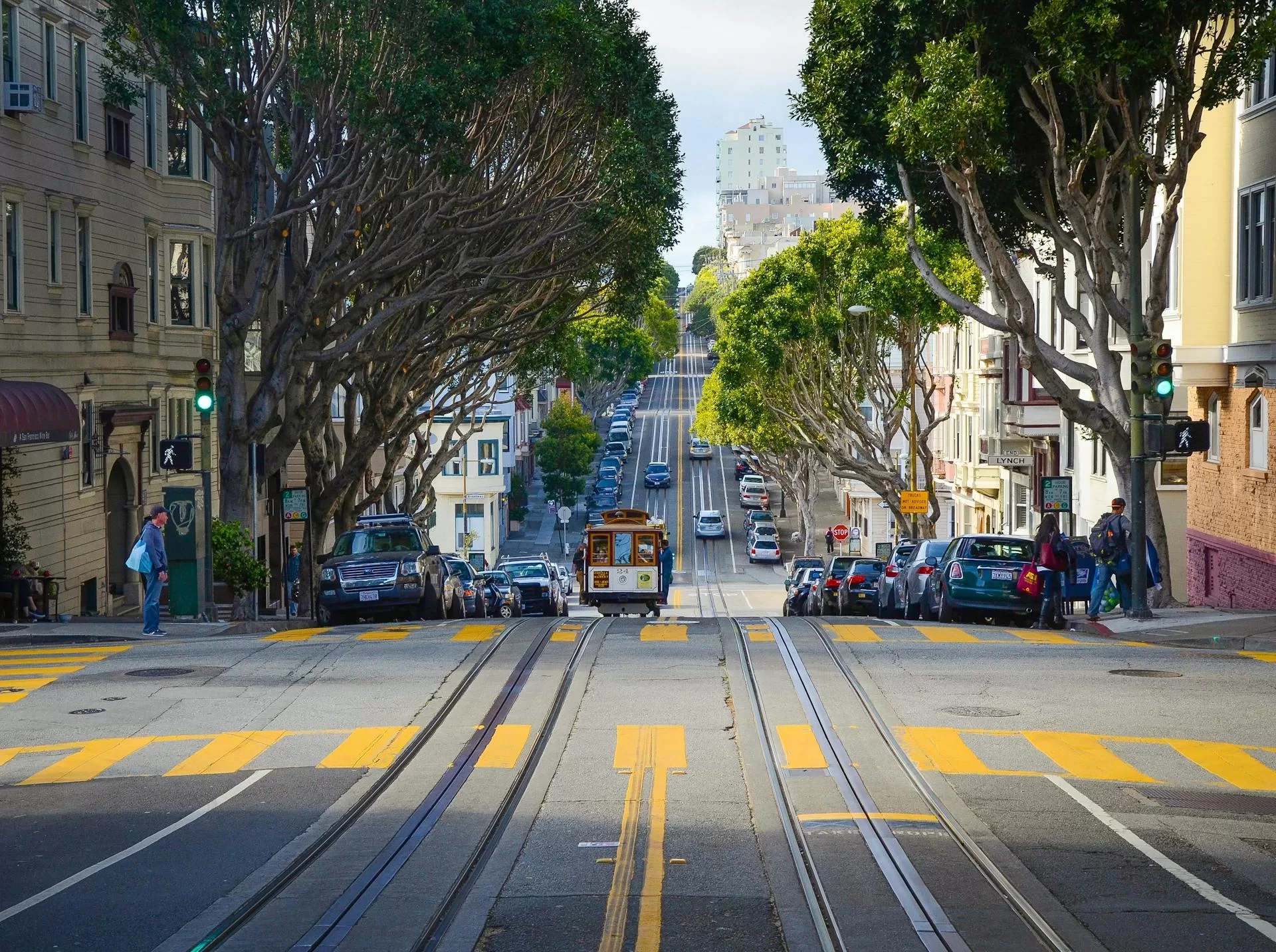 Die traditionelle Straßenbahn fährt auf einer breiten Straße in San Francisco, umgeben von Autos und städtischer Architektur.