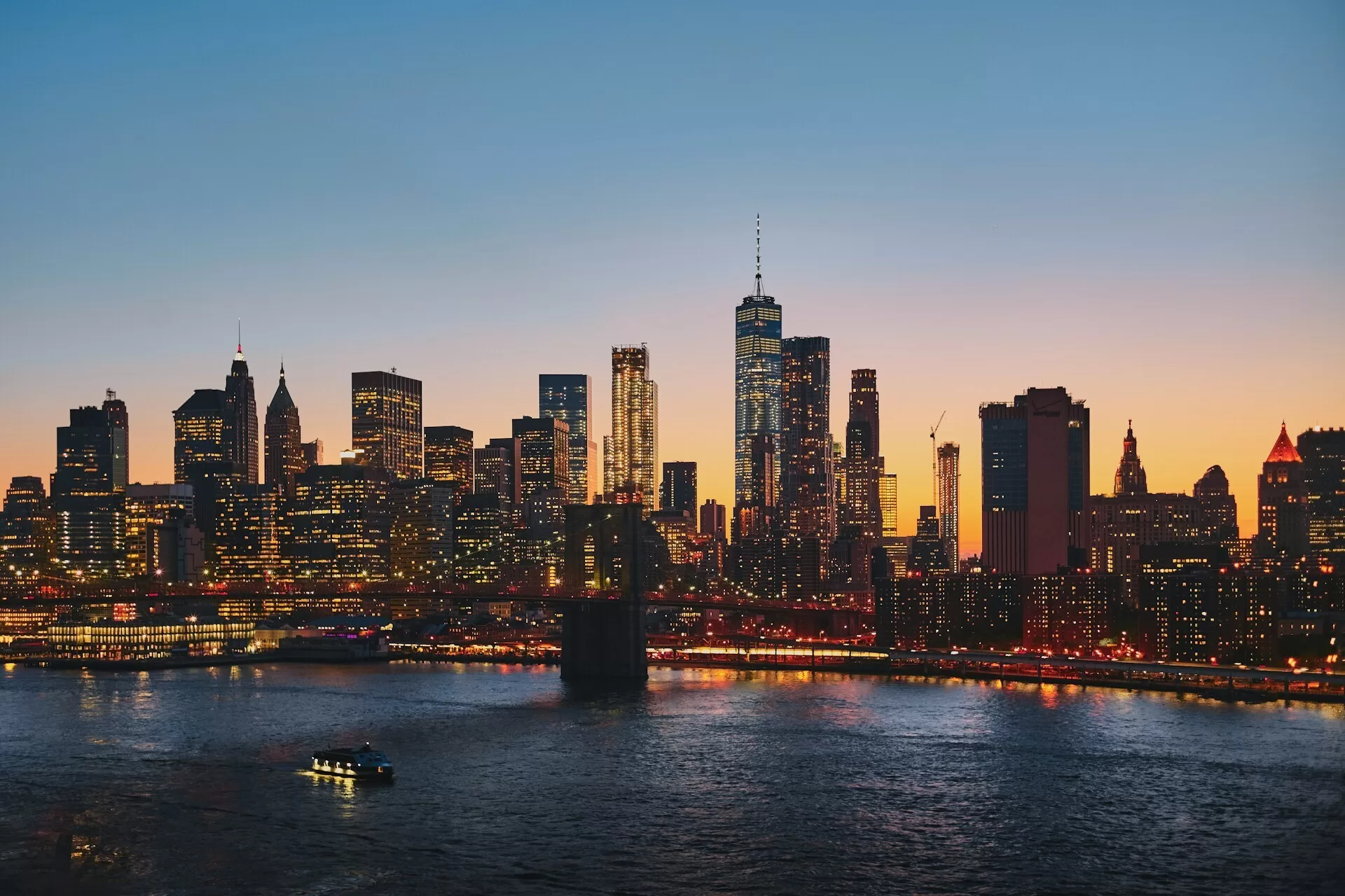 New York skyline bij schemering met verlichte Brooklyn Bridge en fonkelende stadslichten