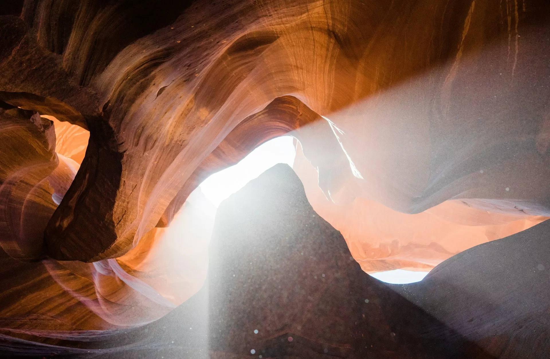 Blick hinauf in den Antelope Canyon, mit wellenförmigen roten Felsformationen und einfallendem Sonnenlicht