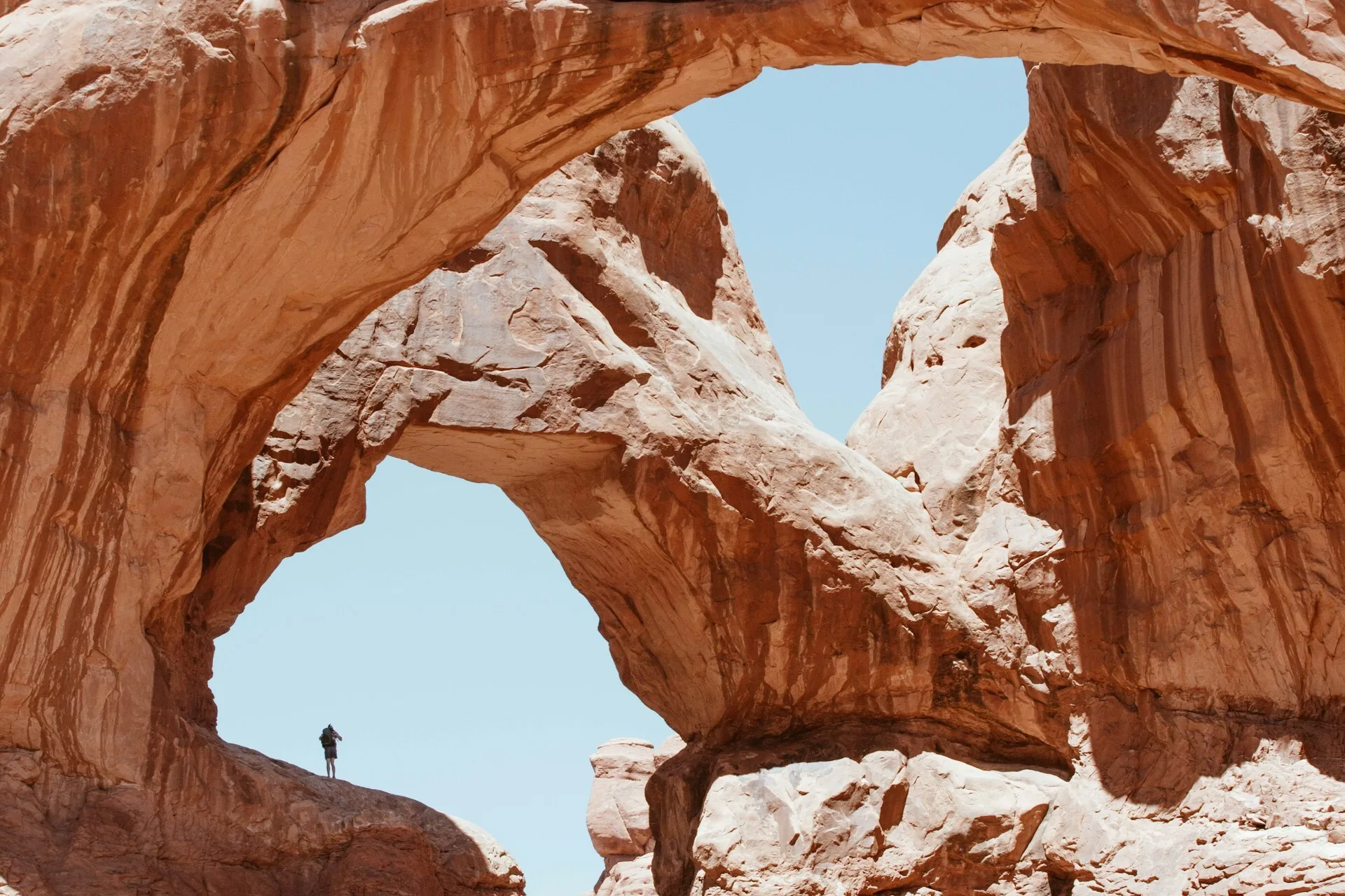 Ee wandelaar op de rotsformaties in de vorm van bogen in Arches National Park