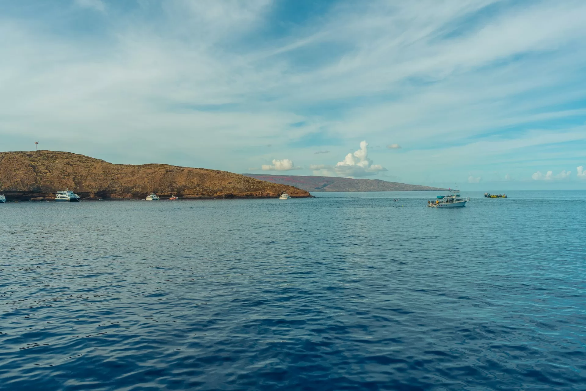 Blick vom Wasser auf den Molokini-Krater und Mauis Küstenlinie mit Booten