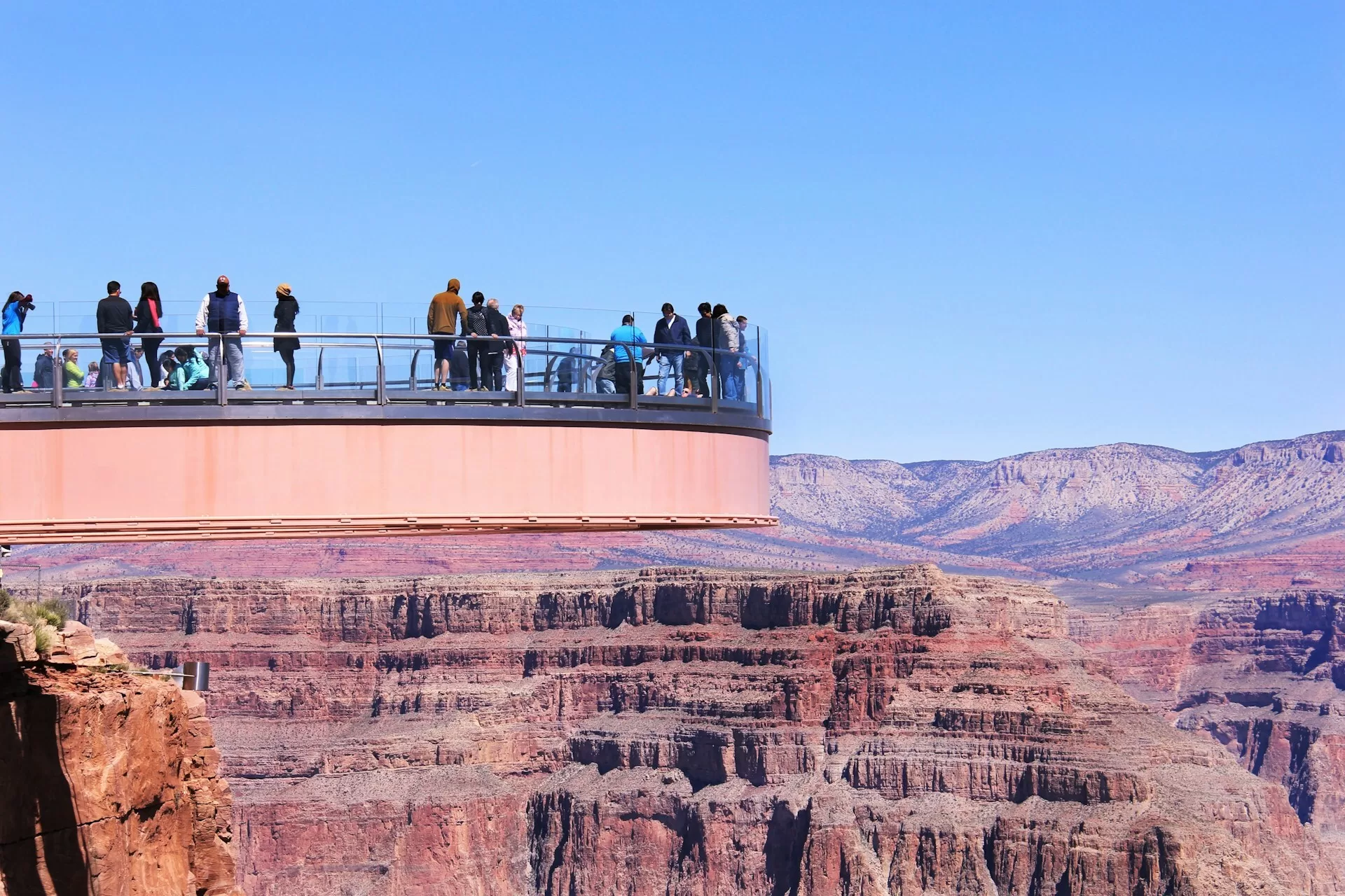 Menschen stehen auf dem Grand Canyon Skywalk und blicken auf den tiefen Canyon und die beeindruckenden Felsformationen
