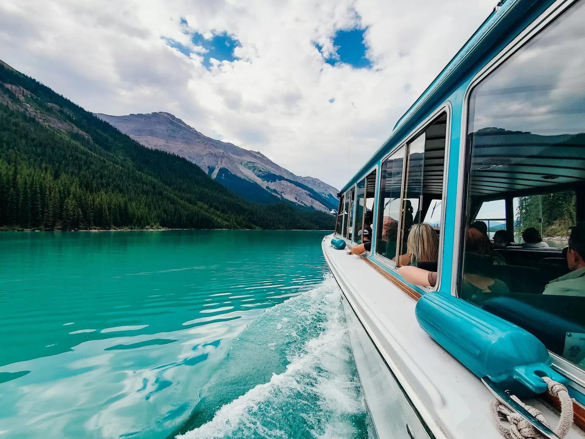 Turquoise water met boot en mensen, bos en berg aan de linkerzijde