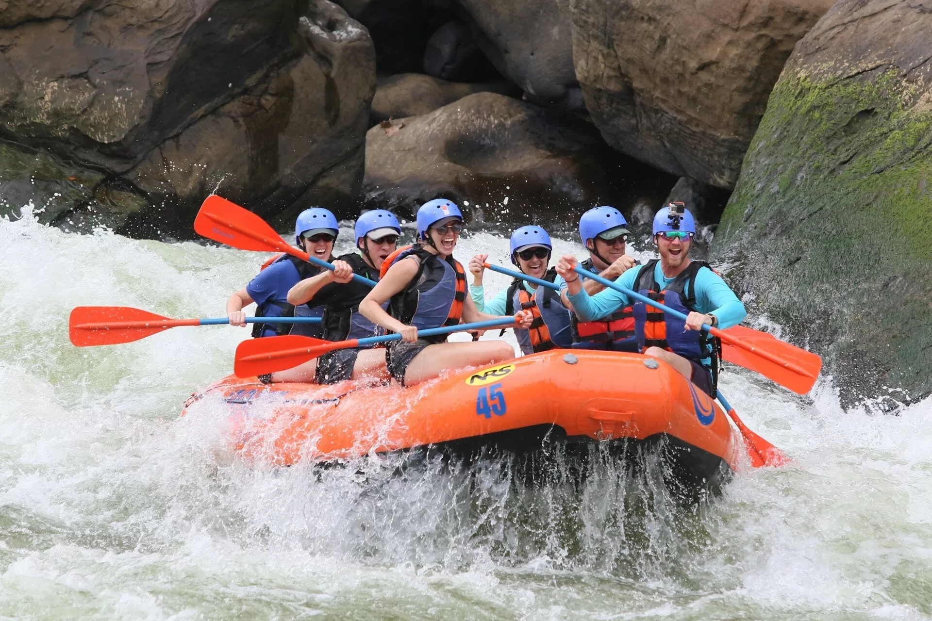 Mensen raften in een oranje boot op wild water