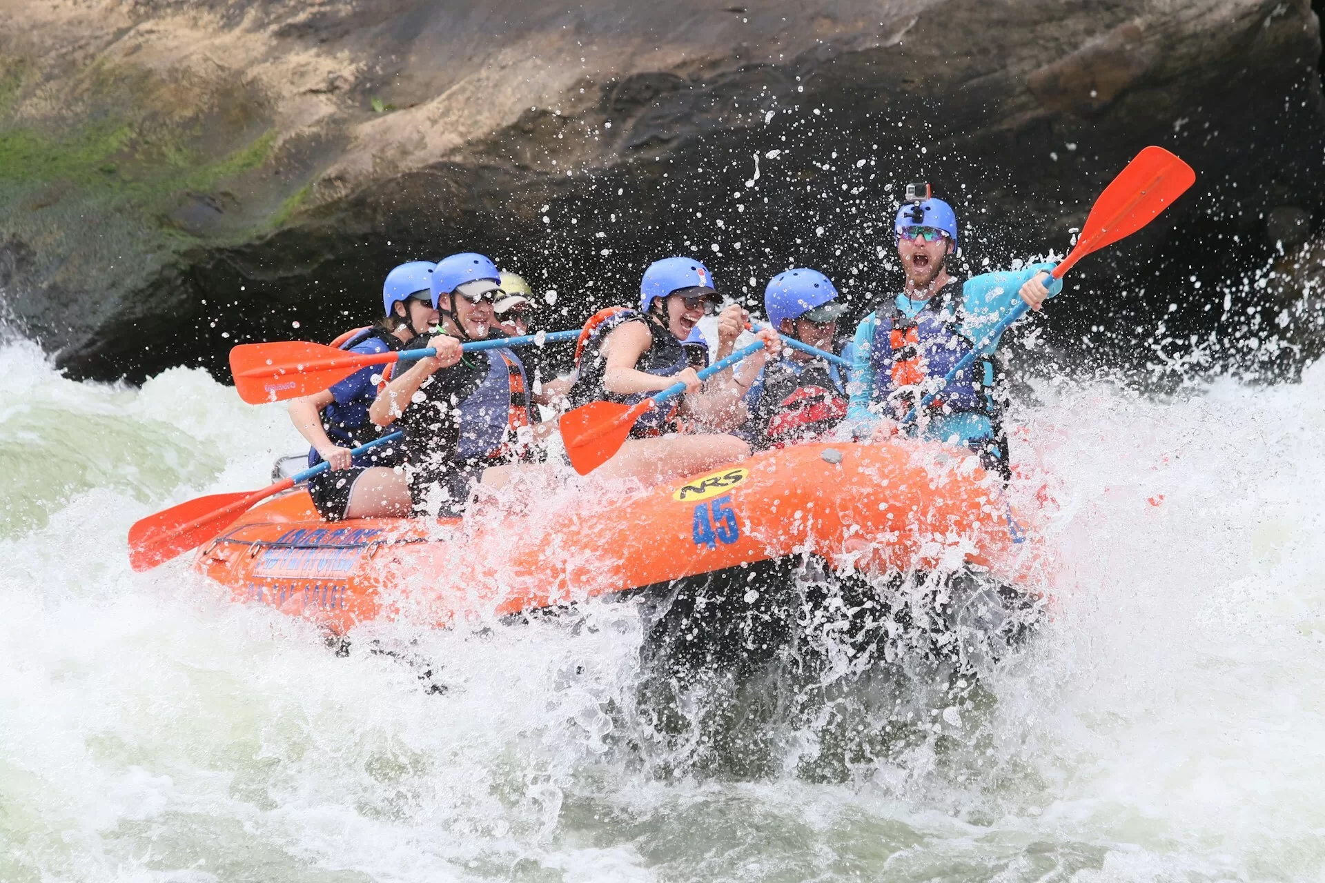 Mensen raften in een oranje boot op wild water