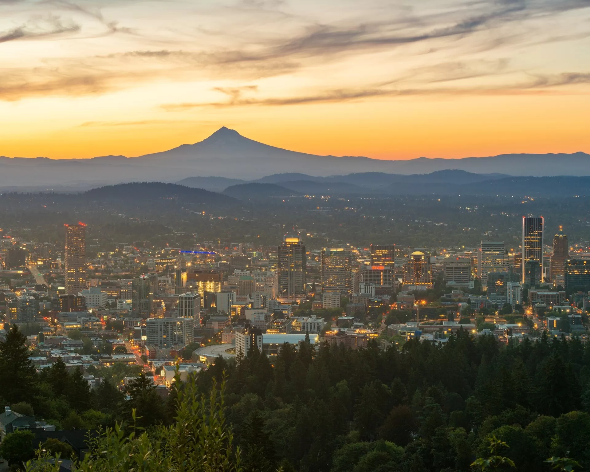 Zicht over de skyline van Portland Oregon met zonsondergang op de achtergrond.