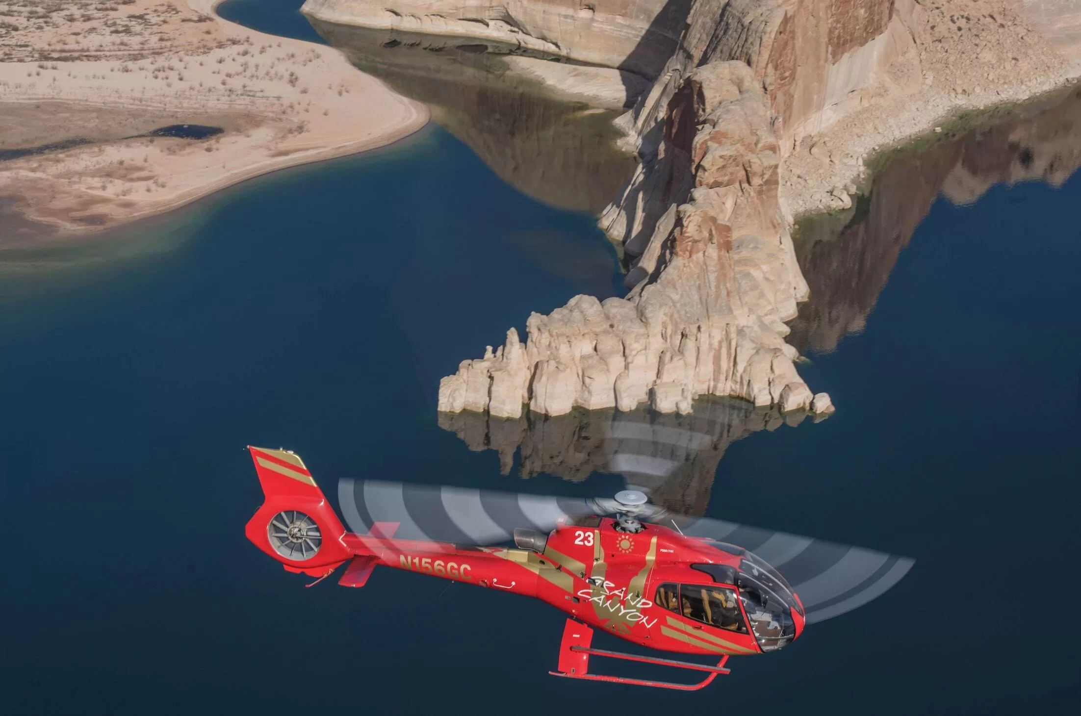 Rot-goldener Hubschrauber fliegt bei Tageslicht über Horseshoe Bend, ikonischer Blick auf Fluss und Schlucht