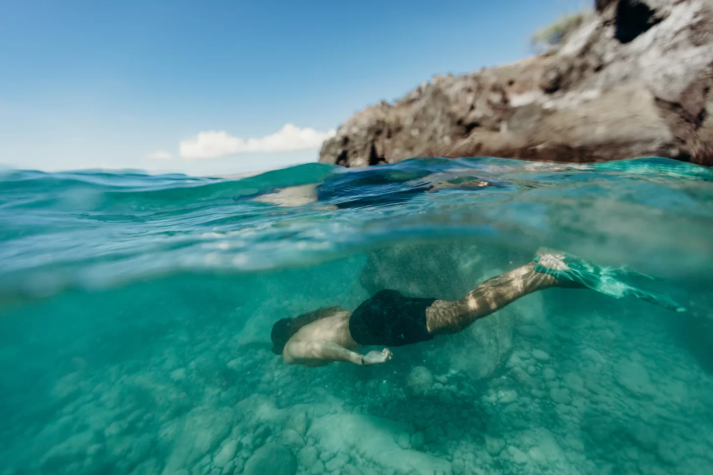 Unterwasser schwimmende Person, halb im und halb aus dem Wasser fotografiert
