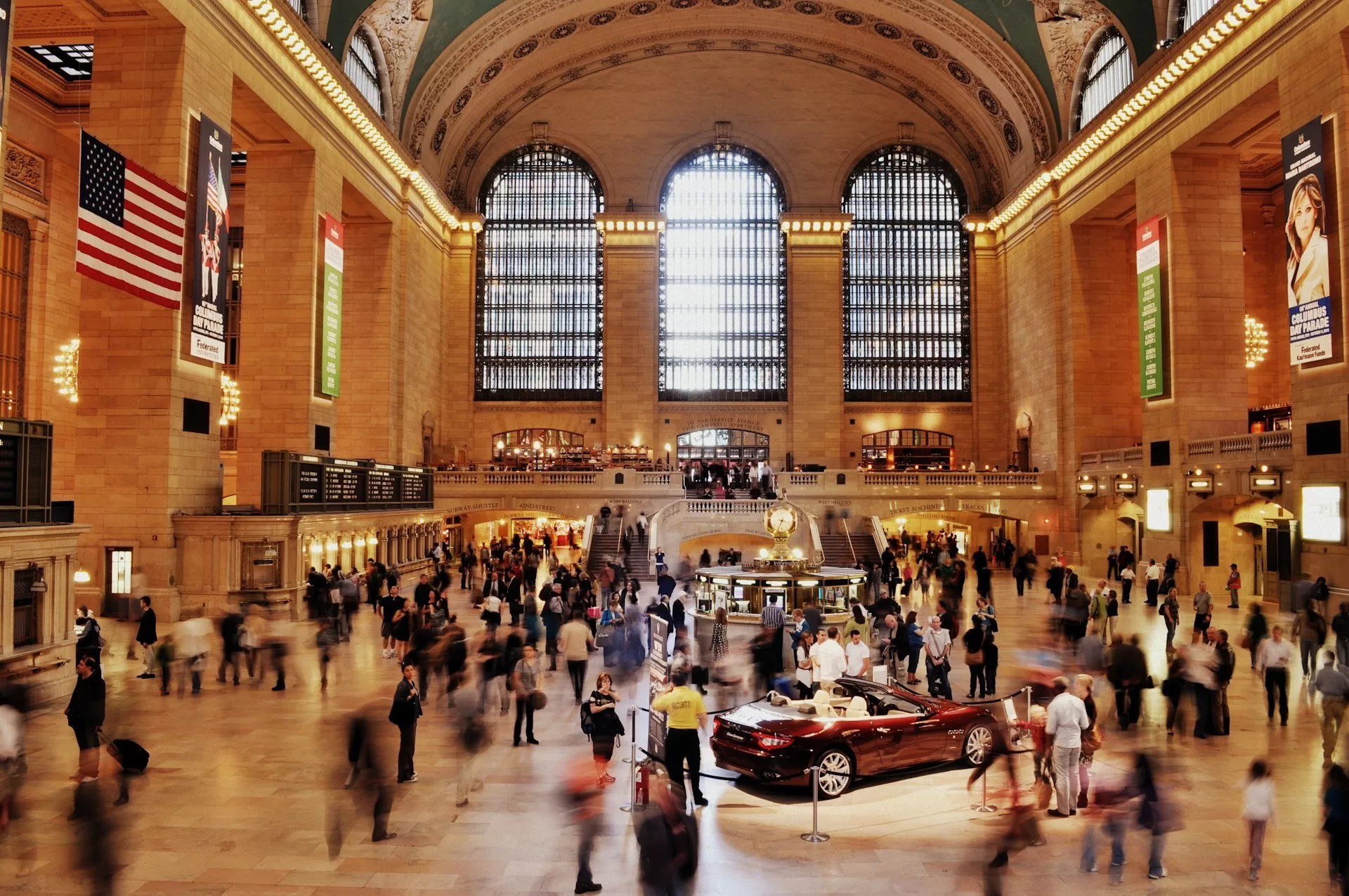 Drukke Grand Central Terminal in New York City met een rode cabrio die tentoon wordt gesteld in het midden