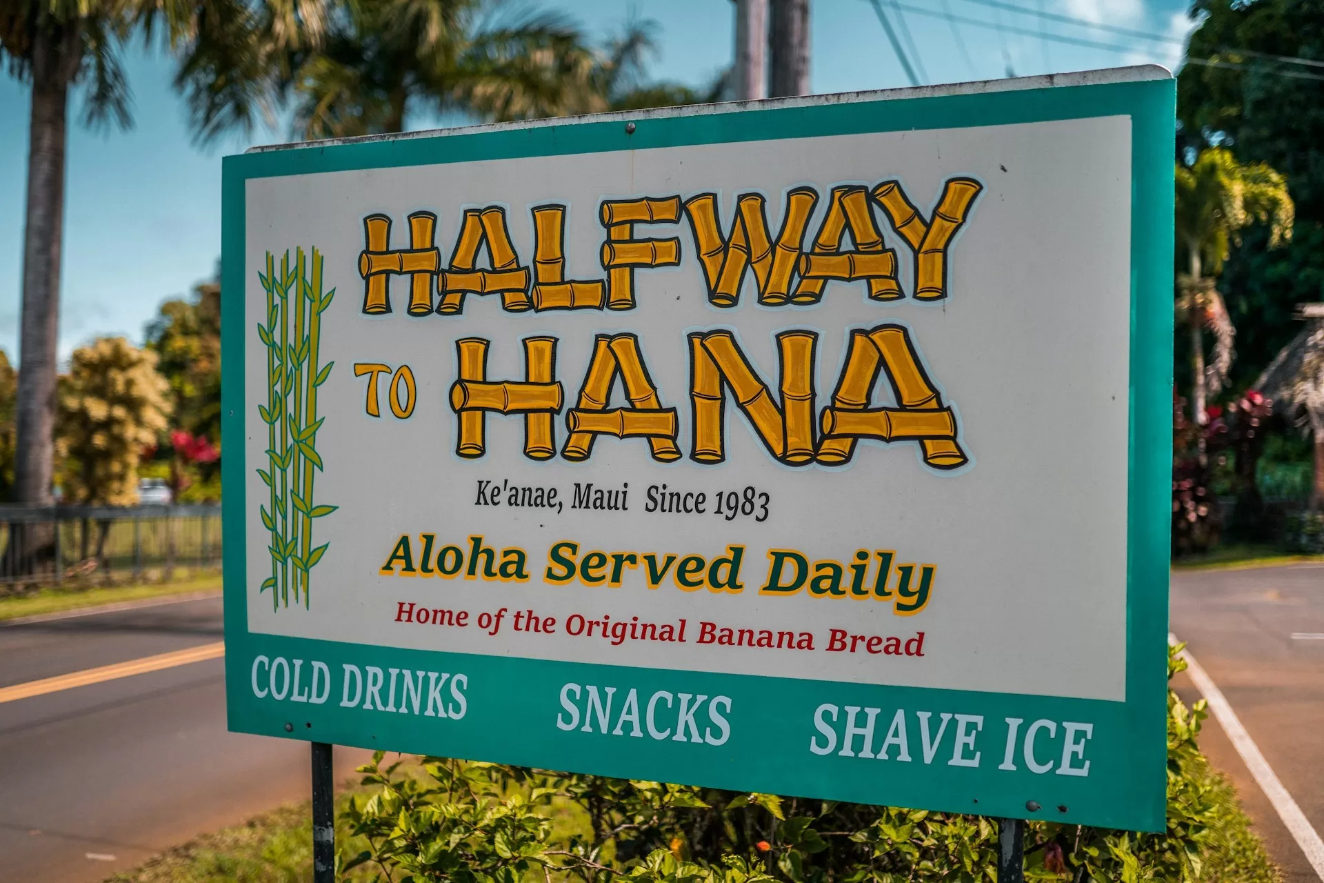 Hellblaues Schild mit der Aufschrift „Halfway Hana“ an der Straße nach Hana in Maui, Hawaii