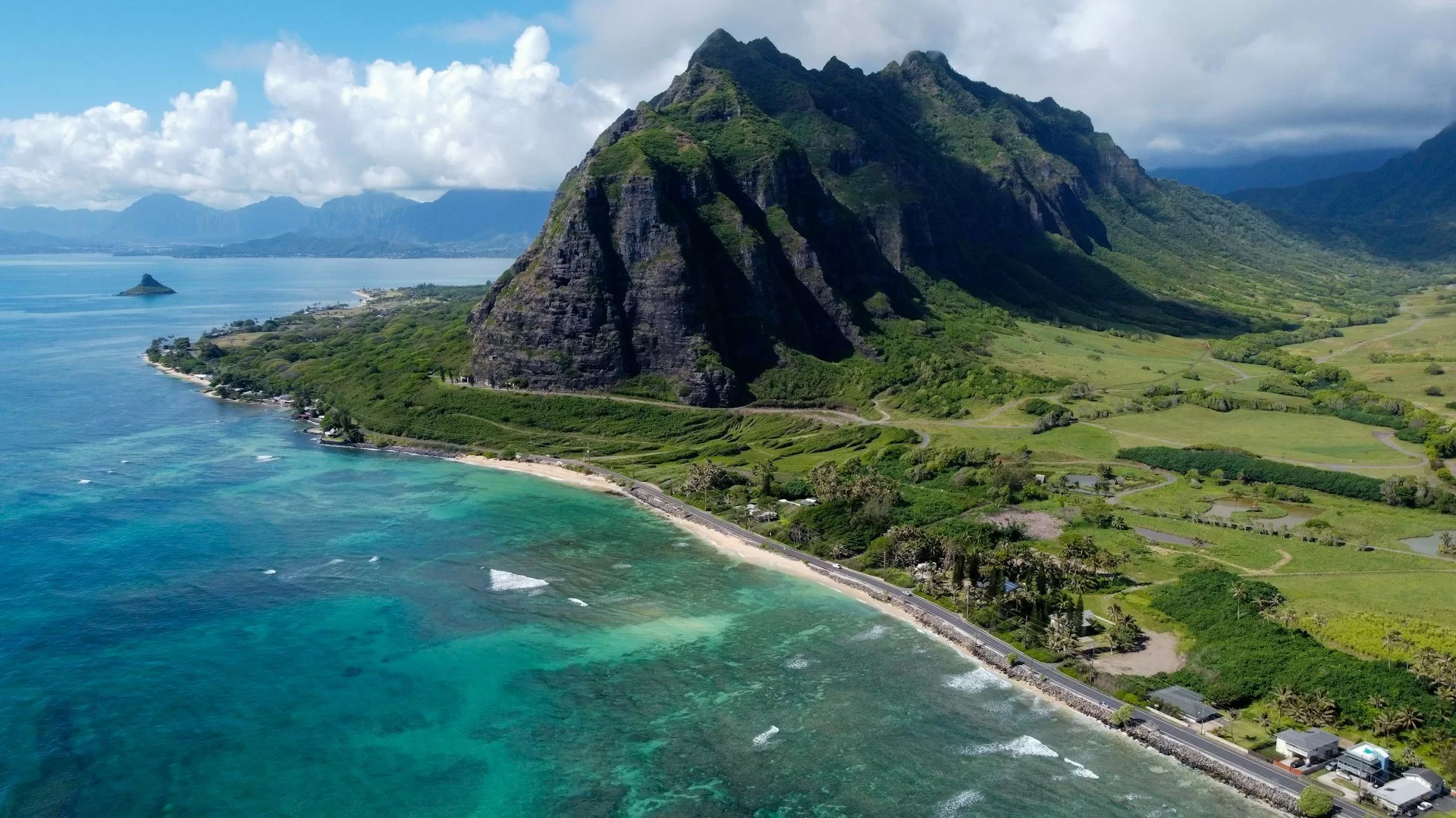 Luftaufnahme der Kualoa Ranch auf Oahu Hawaii, umgeben von blauem Meerwasser und üppiger grüner Landschaft