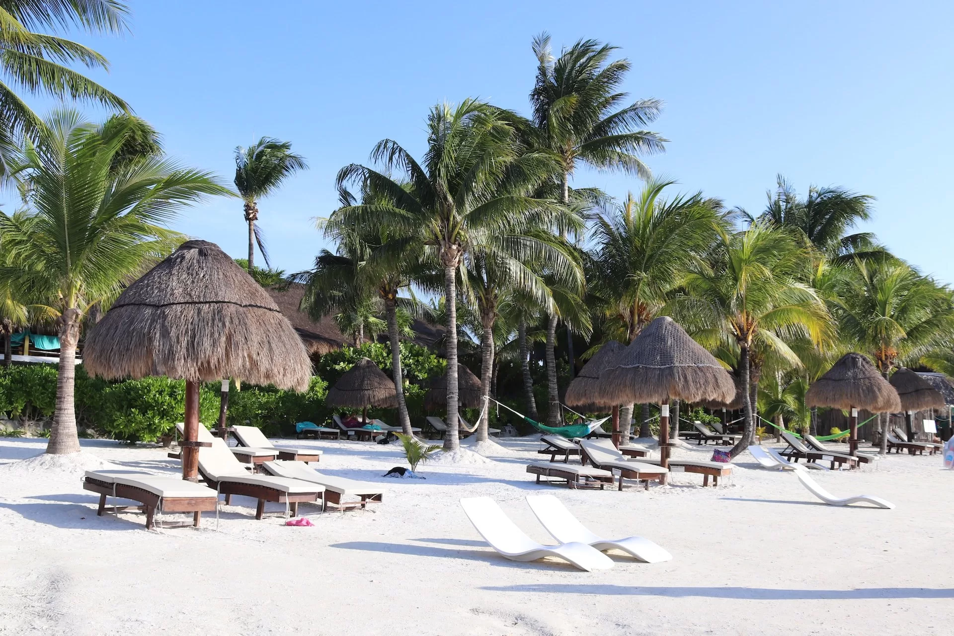 Wit strand met parasols en luxe ligbedden op Isla Holbox, Mexico