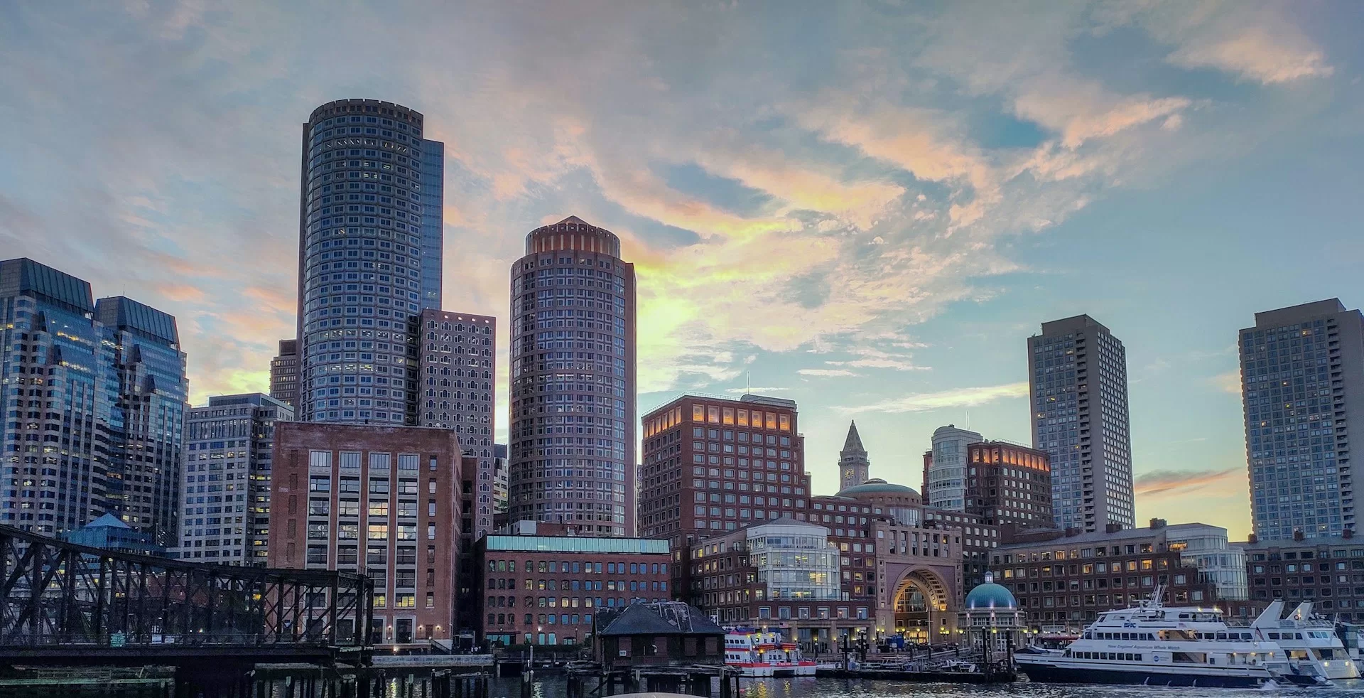 Uitzicht over de haven van Boston, Massachusetts met een ondergaande zon achter een van de wolkenkrabbers