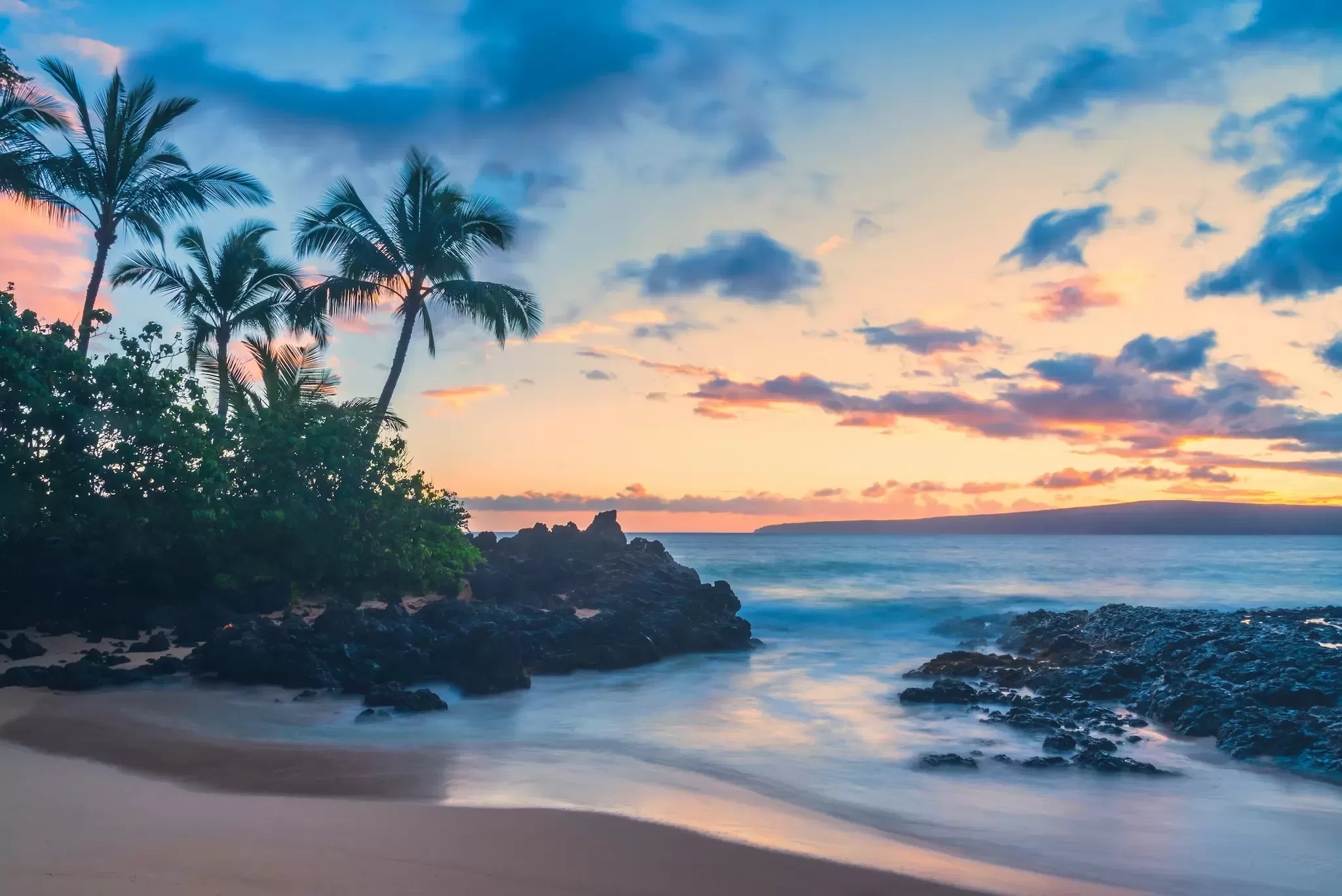 Zonsondergang op een verlaten strand met palmen op Hawaii